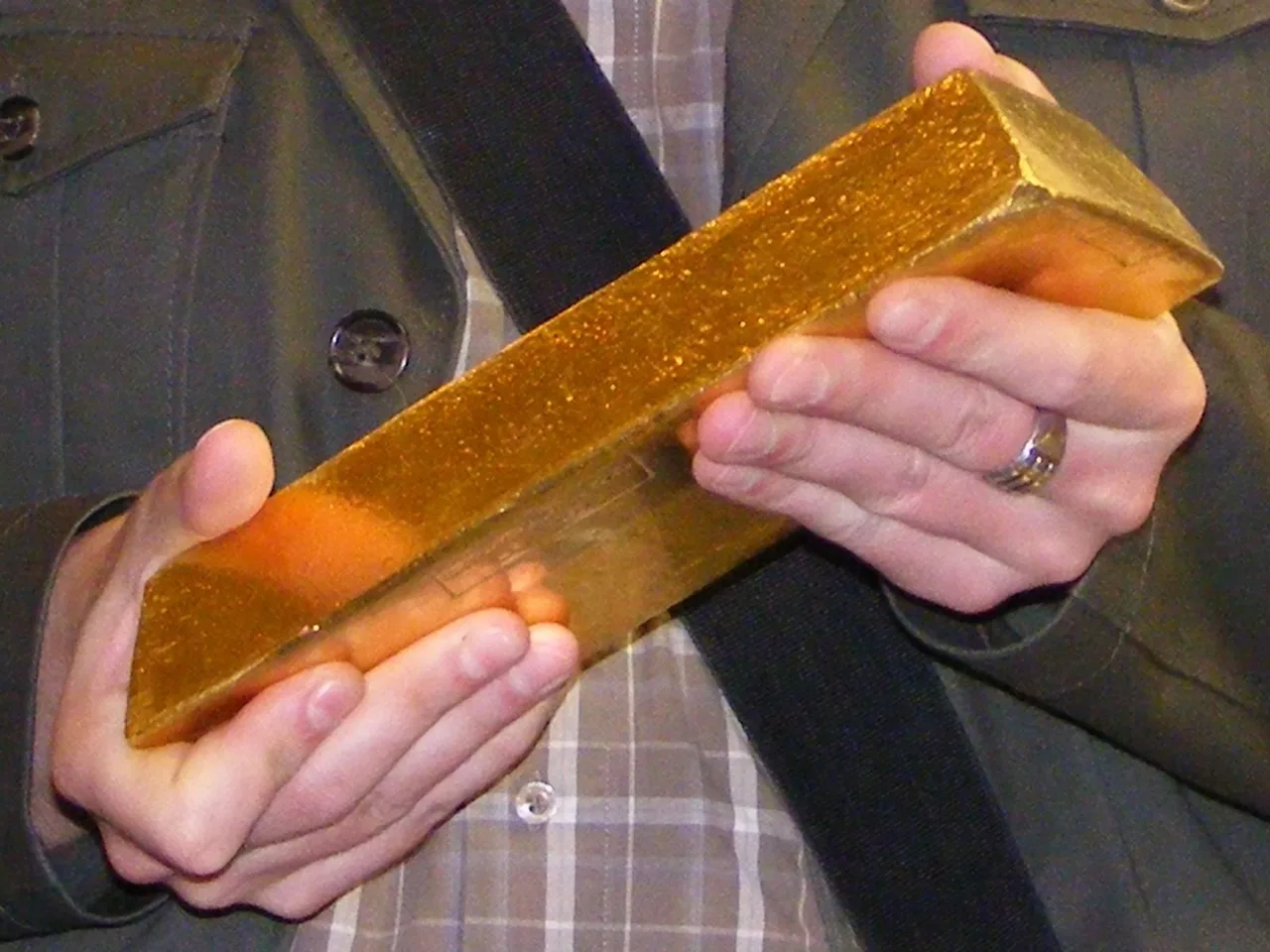 A person holding a large gold bullion bar