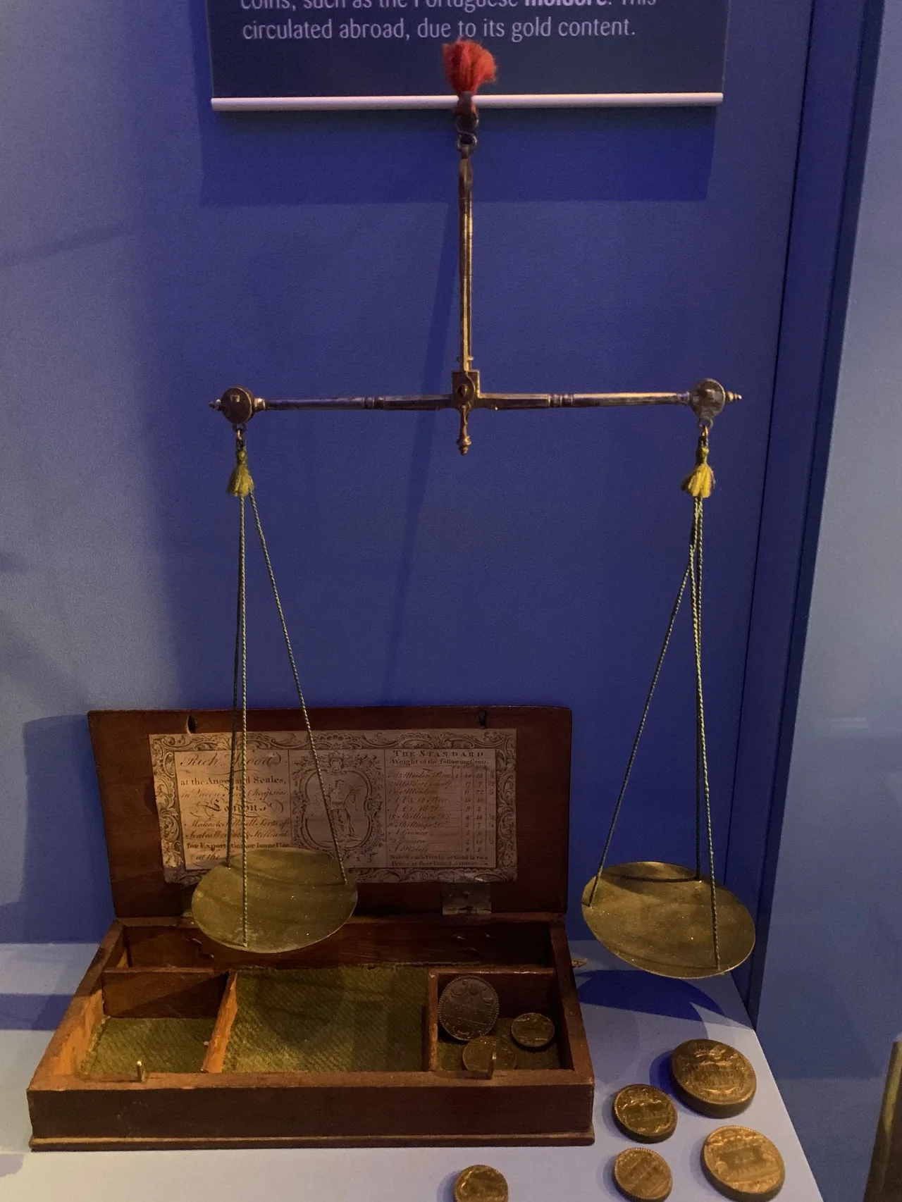 A historical balance scale displayed with coins